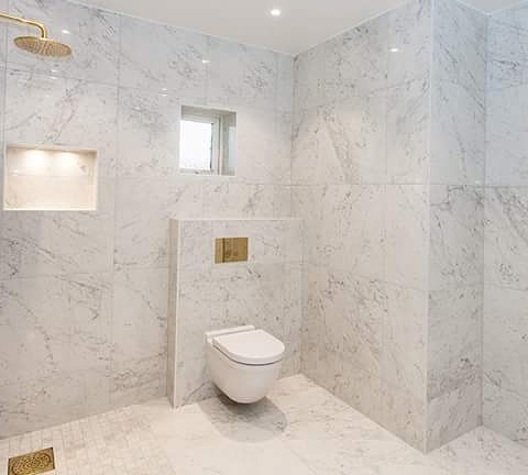 Nyrenovert badrum med golv och väggar i marmor med mässingsdetaljer